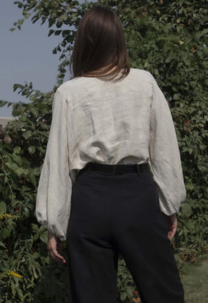 woman in oatmeal linen asymmetrical blouse with black slacks and black belt