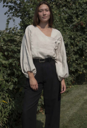 woman in oatmeal linen asymmetrical blouse with black slacks and black belt