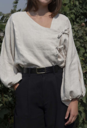 woman in oatmeal linen asymmetrical blouse with black slacks and black belt