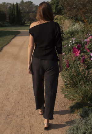 woman in black barrel leg trousers and black rib asymmetrical top