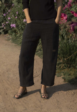 woman in black barrel leg trousers and black rib asymmetrical top