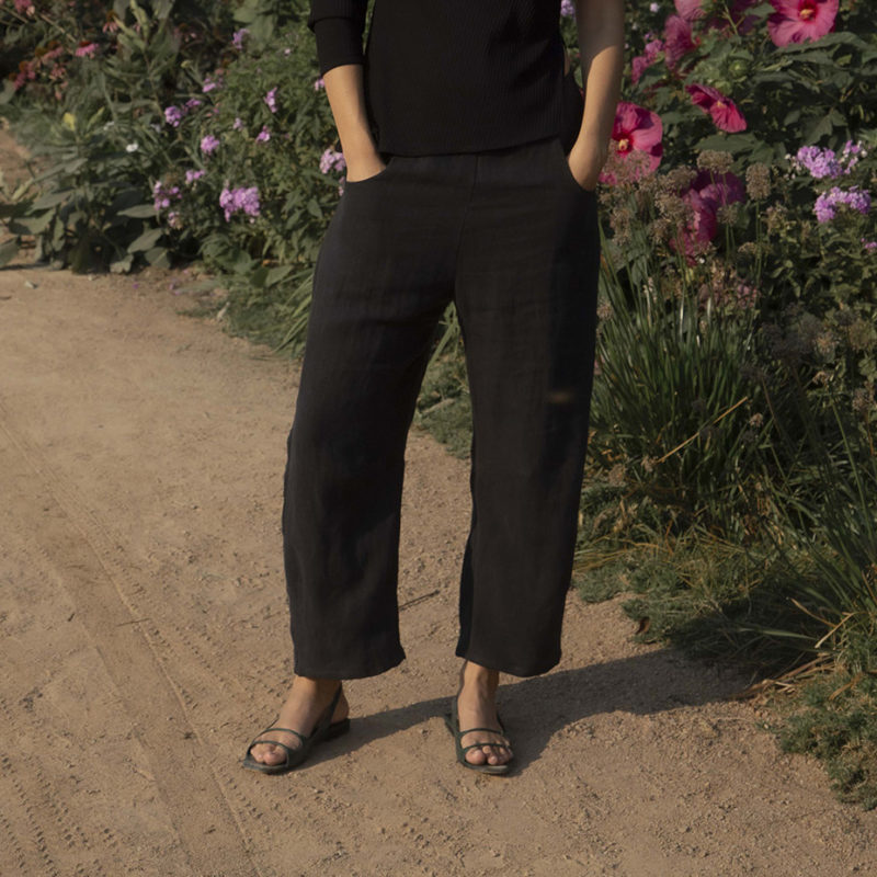 woman in black barrel leg trousers and black rib asymmetrical top