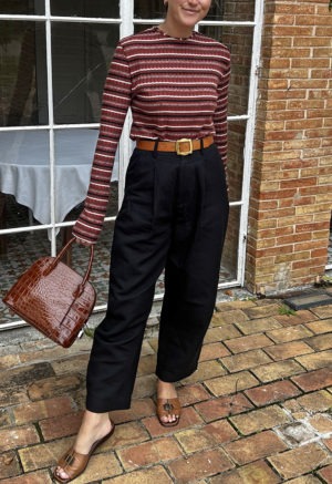 woman in red stripe cropped long sleeve top and black pants standing on a street