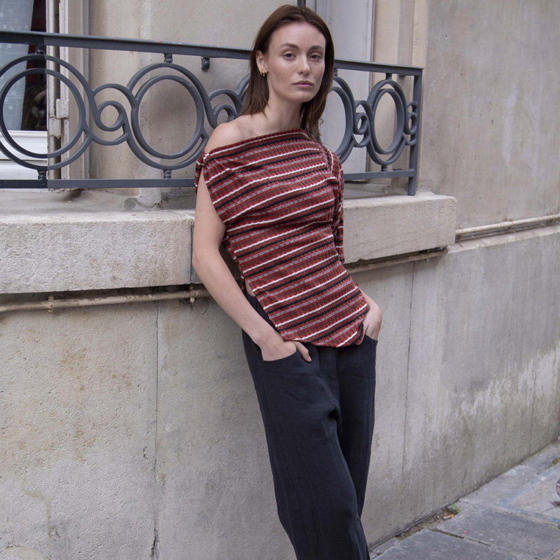 woman in red strip off the shoulder top and black pants walking on a street