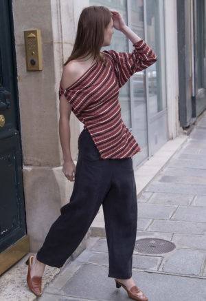 woman in red strip off the shoulder top and black pants walking on a street