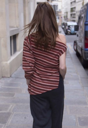 woman in red strip off the shoulder top and black pants walking on a street