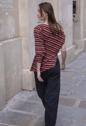 woman in red strip off the shoulder top and black pants walking on a street