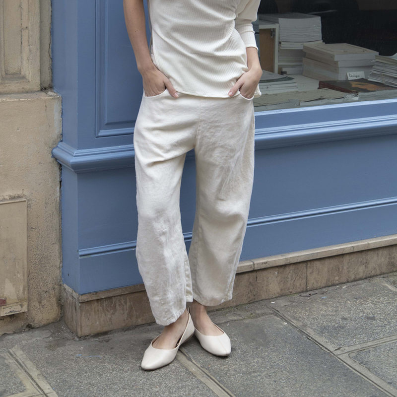 woman in cream pants, cream rib top and cream shoes standing on street