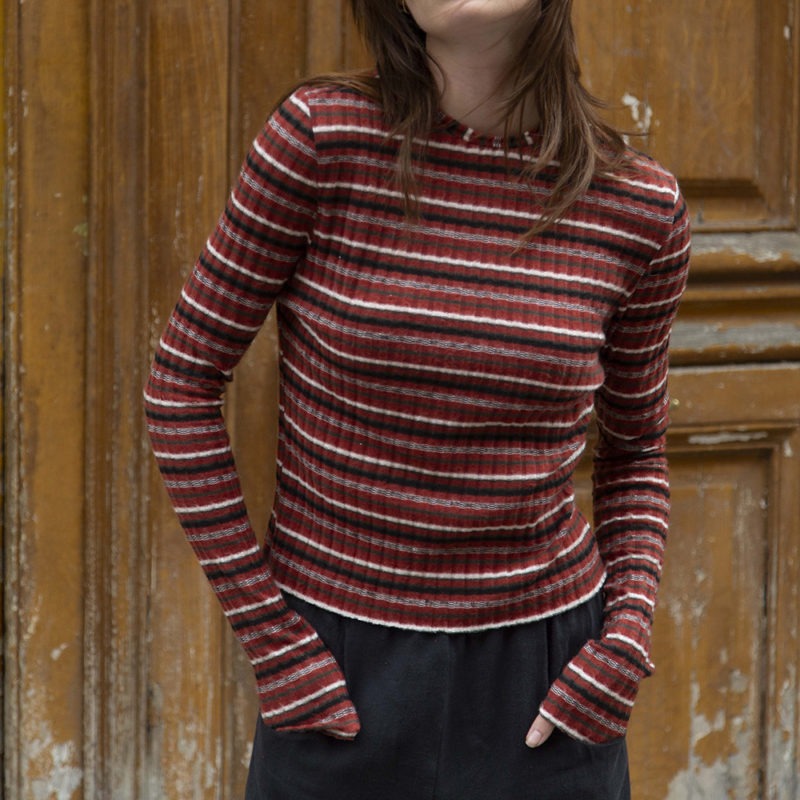 woman in red stripe cropped long sleeve top and black pants standing on a street