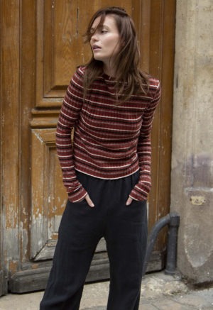 woman in red stripe cropped long sleeve top and black pants standing on a street