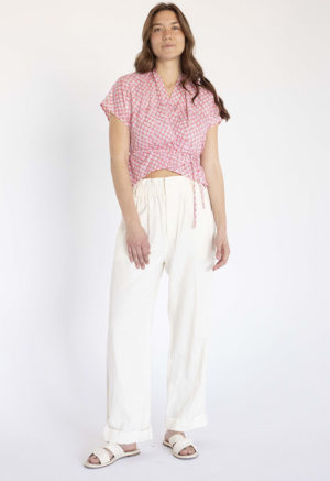 woman in pink and white floral short sleeve cropped wrap top and white wide-leg trousers