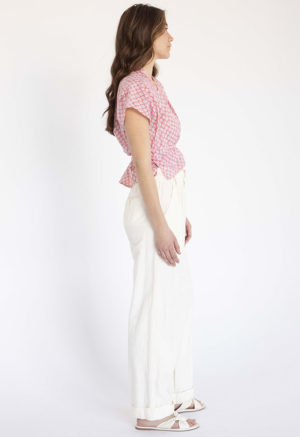 woman in pink and white floral short sleeve cropped wrap top and white wide-leg trousers
