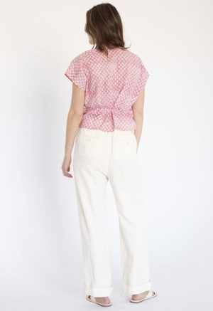 woman in pink and white floral short sleeve cropped wrap top and white wide-leg trousers