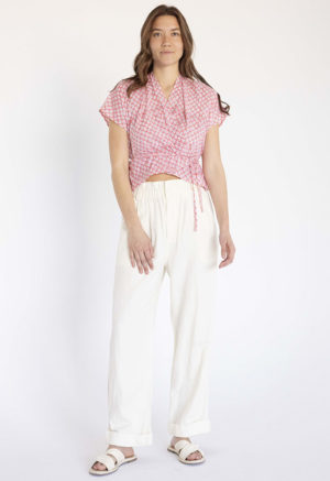 woman in pink and white floral short sleeve cropped wrap top and white wide-leg trousers