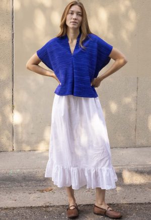 woman in cobalt blue v-neck top over white cotton skirt