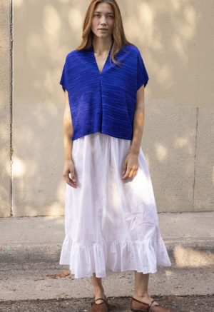 woman in cobalt blue v-neck top over white cotton skirt