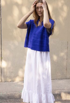 woman in cobalt blue v-neck top over white cotton skirt