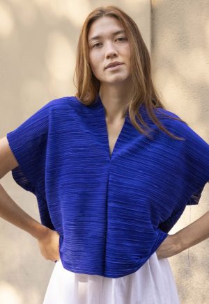 woman in cobalt blue v-neck top over white cotton skirt