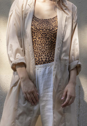 woman in leopard print tank top, white pants, tan sheer jacket