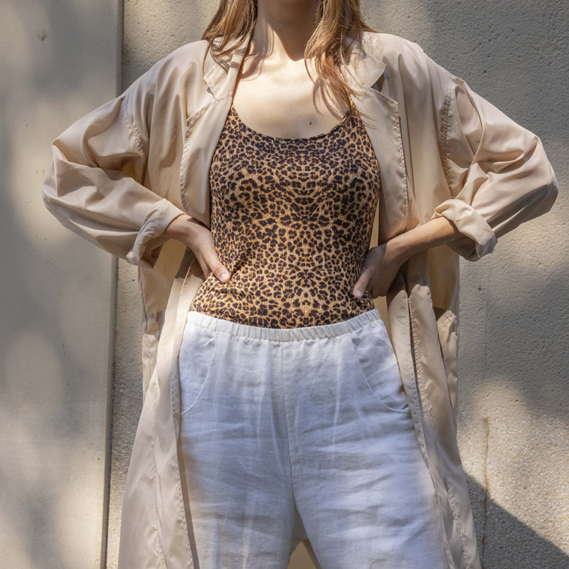 woman in leopard print tank top, white pants, tan sheer jacket