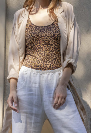 woman in leopard print tank top, white pants, tan sheer jacket