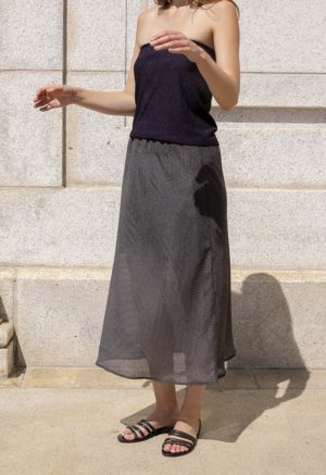 woman wearing sheer dark hazy green slip skirt, black tube top and black sandals.