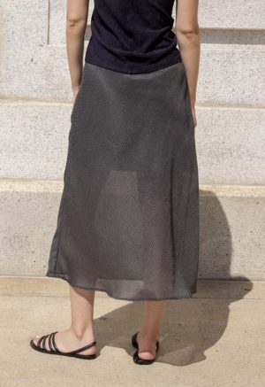 woman wearing sheer dark hazy green slip skirt, black tube top and black sandals.