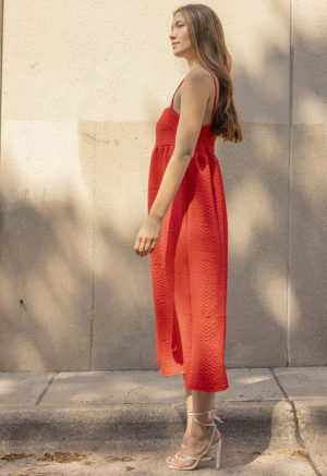 woman in bright red sundress standing in speckled sunlight