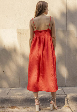 woman in bright red sundress standing in speckled sunlight