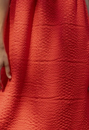 woman in bright red sundress standing in speckled sunlight