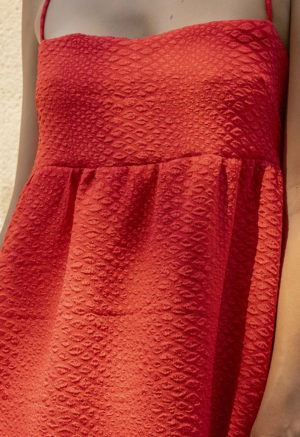 woman in bright red sundress standing in speckled sunlight