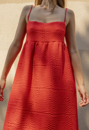 woman in bright red sundress standing in speckled sunlight