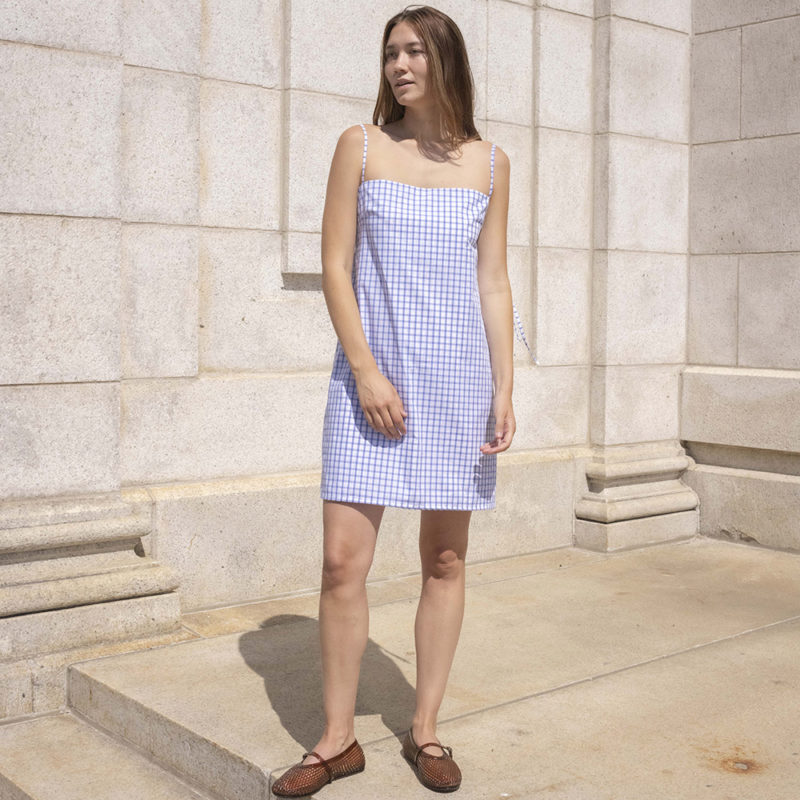 woman in white and blue window pane slip dress with brown jelly shoes