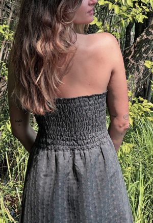 woman in dark grey charcoal strapless maxi dress standing in front of green grasses and trees