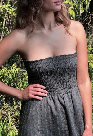 woman in dark grey charcoal strapless maxi dress standing in front of green grasses and trees