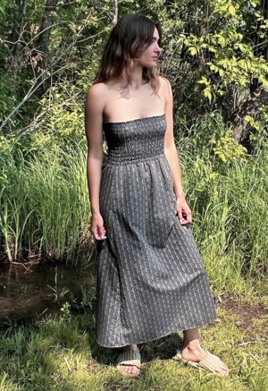 woman in dark grey charcoal strapless maxi dress standing in front of green grasses and trees