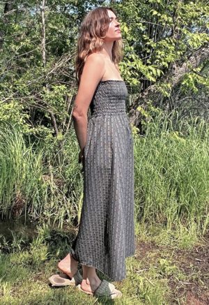 woman in dark grey charcoal strapless maxi dress standing in front of green grasses and trees
