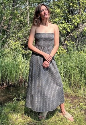 woman in dark grey charcoal strapless maxi dress standing in front of green grasses and trees