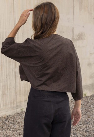 woman in dark brown and black floral boatneck top and black trousers
