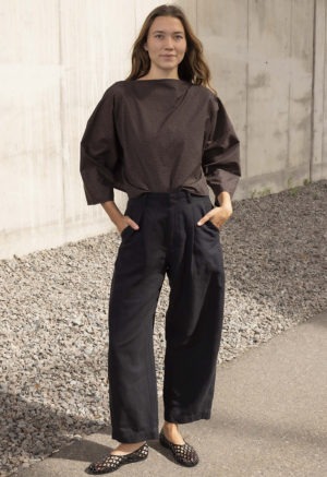 woman in dark brown and black floral boatneck top and black trousers