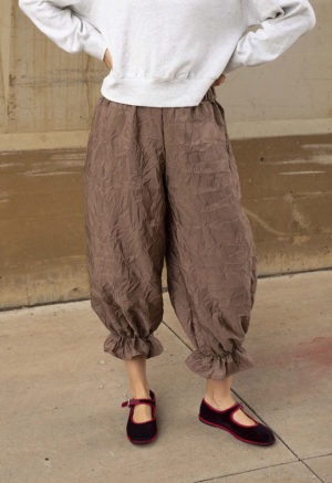 woman in mauve pant with ruffle cuff and maroon and red ballet flats and light grey sweatshirt