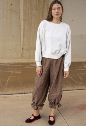 woman in mauve pant with ruffle cuff and maroon and red ballet flats and light grey sweatshirt