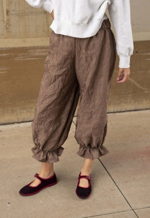 woman in mauve pant with ruffle cuff and maroon and red ballet flats and light grey sweatshirt