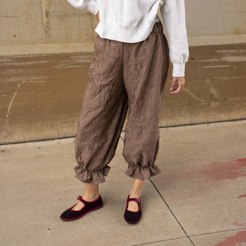 woman in mauve pant with ruffle cuff and maroon and red ballet flats and light grey sweatshirt