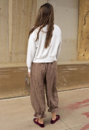 woman in mauve pant with ruffle cuff and maroon and red ballet flats and light grey sweatshirt