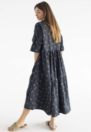 woman in black cotton tiered lapel dress with palm tree pattern.