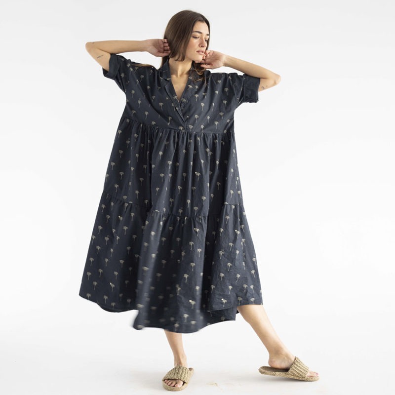 woman in black cotton tiered lapel dress with palm tree pattern.