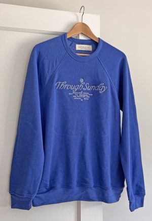 blue sweatshirt with white embroidered writing at chest