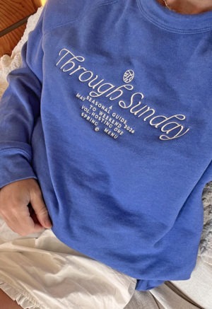 blue sweatshirt with white embroidered writing at chest