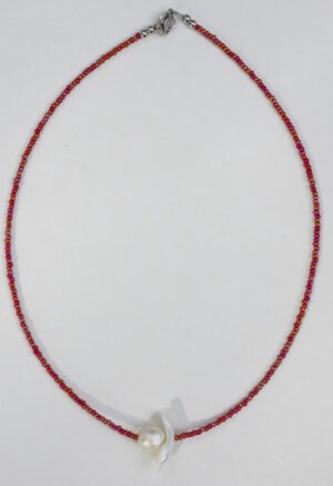 red necklace with pearl center on white backdrop